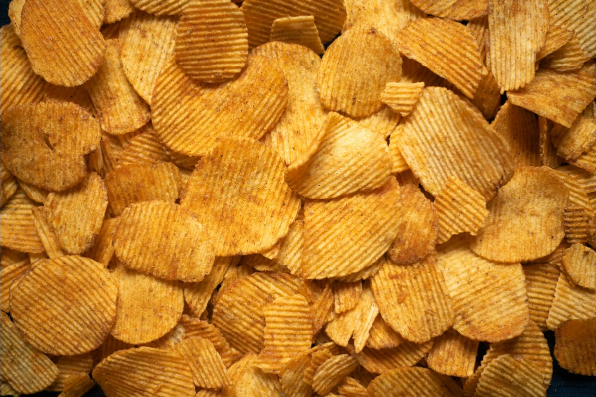 A delicious pile of golden crispy potato chips viewed from above.
